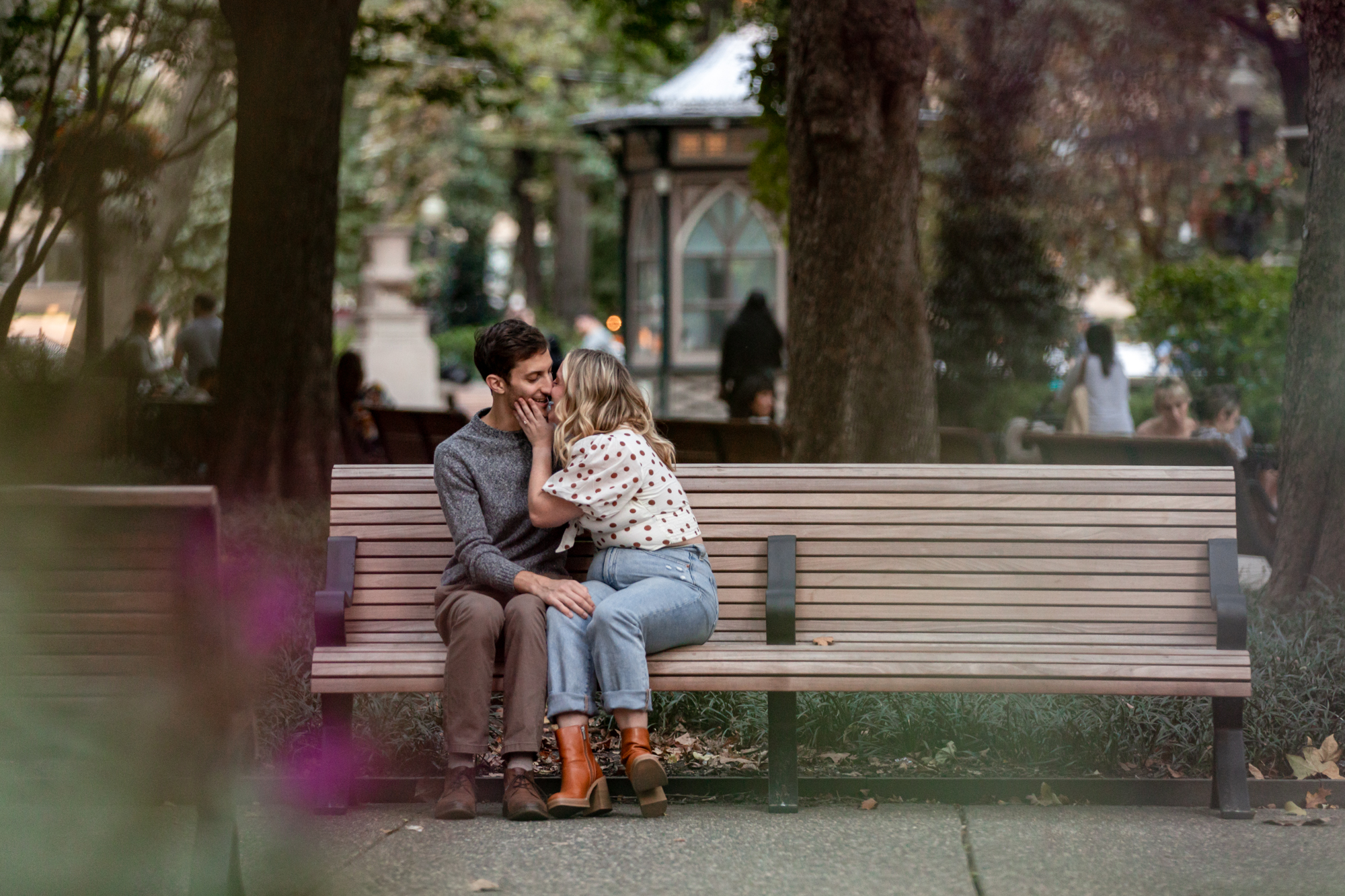 a newly engaged couple kisses on a bench in rittenhouse square