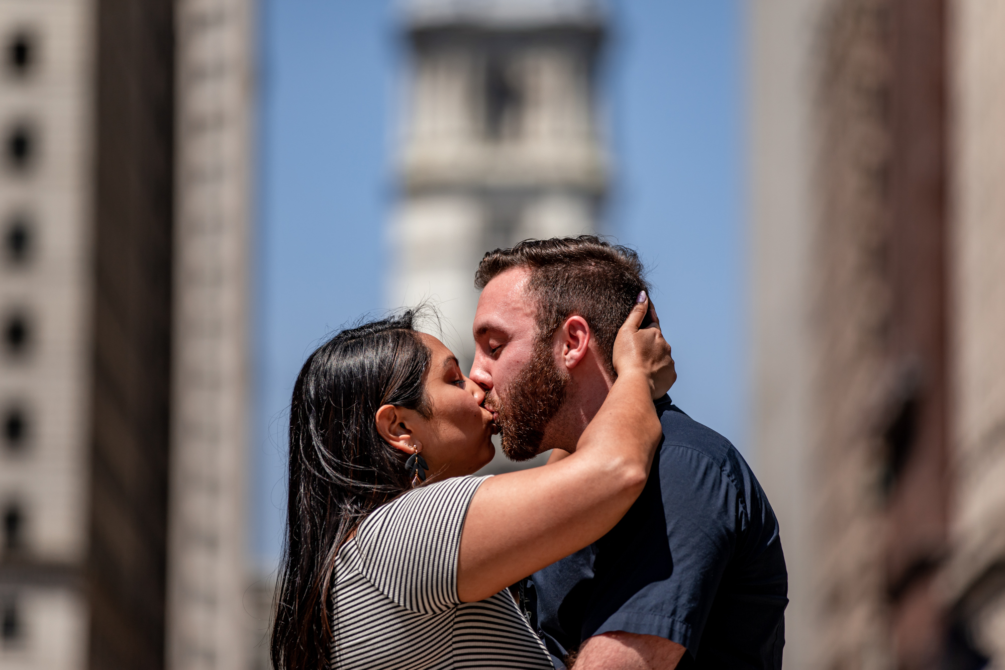 a newly engaged couple kissing in front of city hall