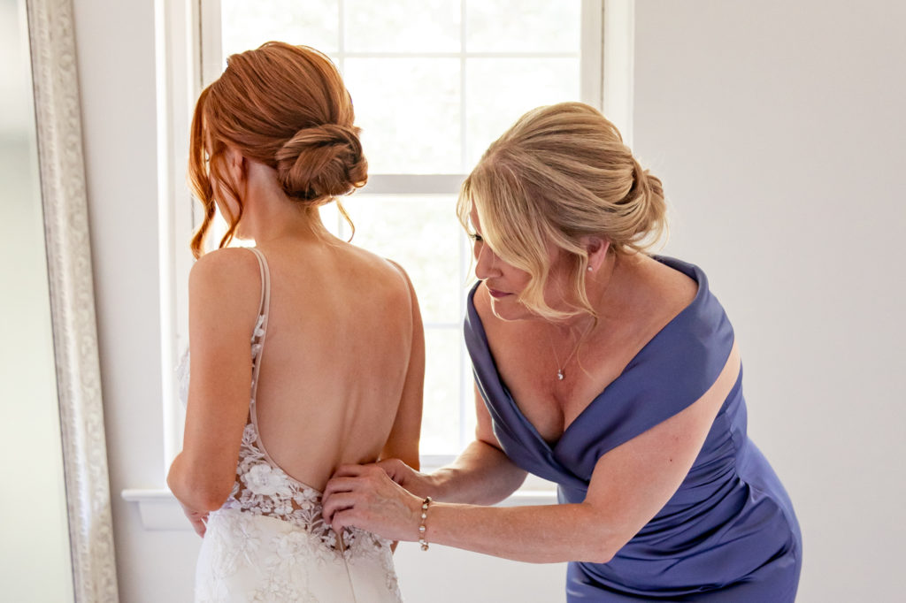 mother of the bride helping bride get dressed