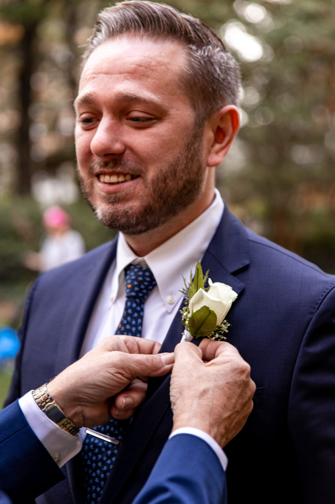 father of the groom pinning a boutonnière on his son