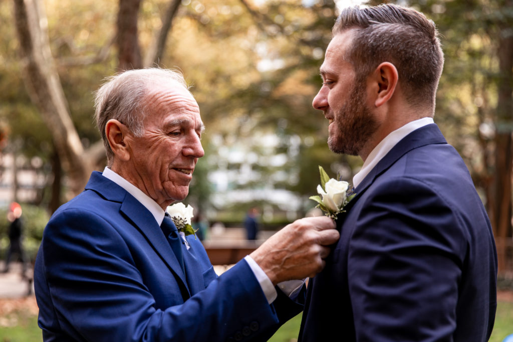father of the groom pinning a boutonnière on his son