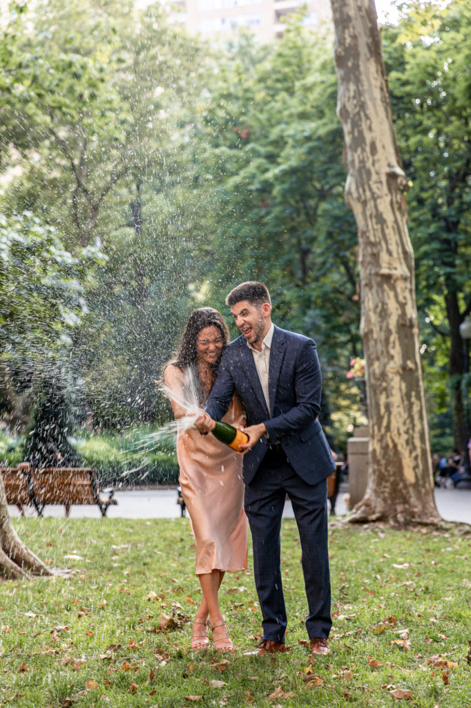 newly engaged couple spraying champagne in rittenhouse square