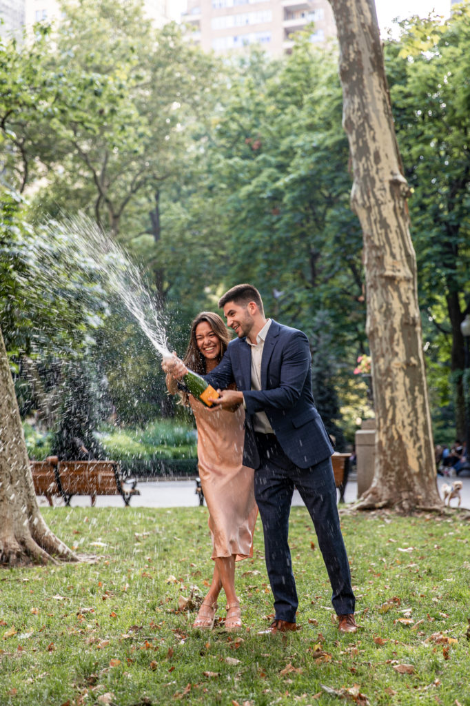 newly engaged couple spraying champagne in rittenhouse square