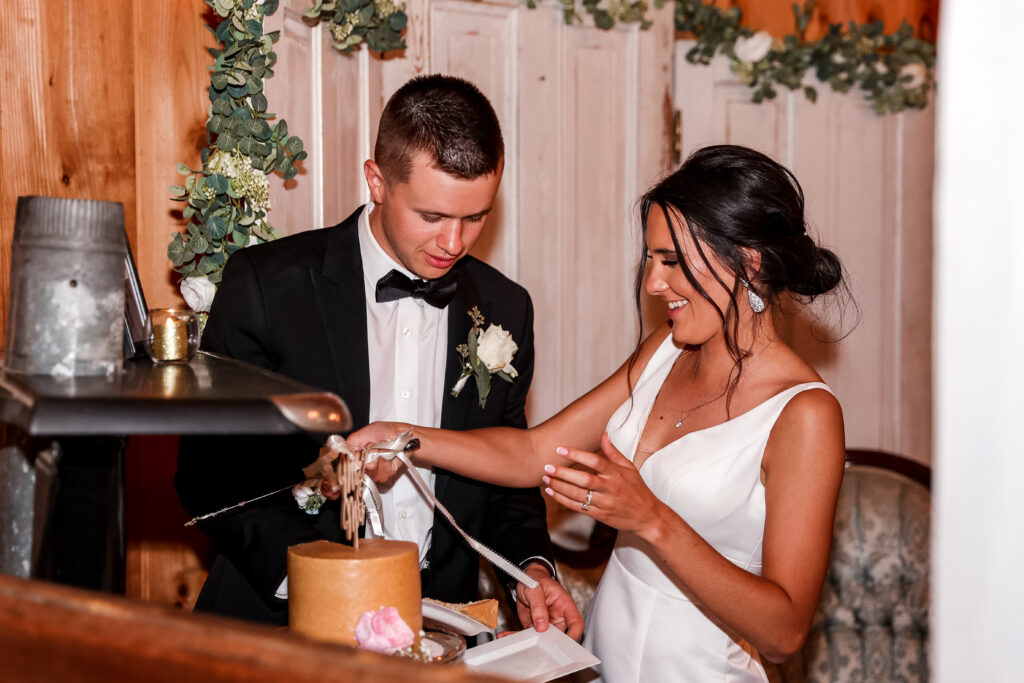 cake cutting during a barn reception at a white chimneys estate wedding
