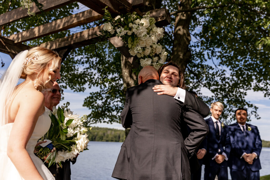 father of the bride hugging the groom during the ceremony