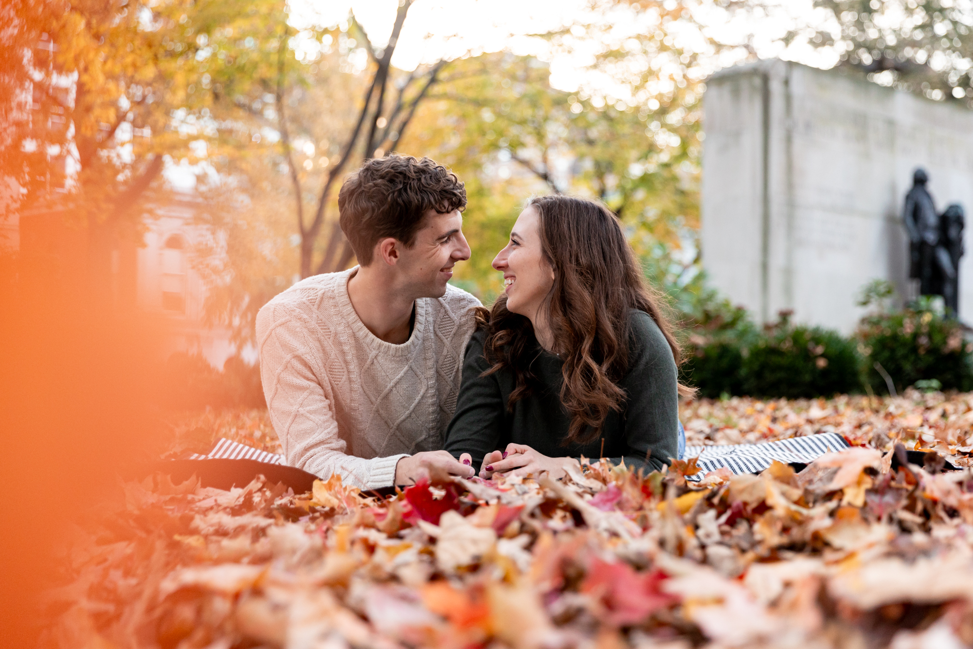 fall engagement photo laying in the leaves in washington square park in philadelphia, pennsylvania