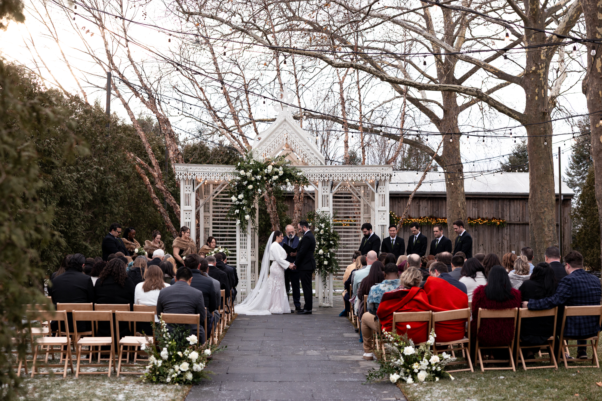 a bride and groom hold hands during an outdoor winter wedding ceremony at Terrain at Styer's.