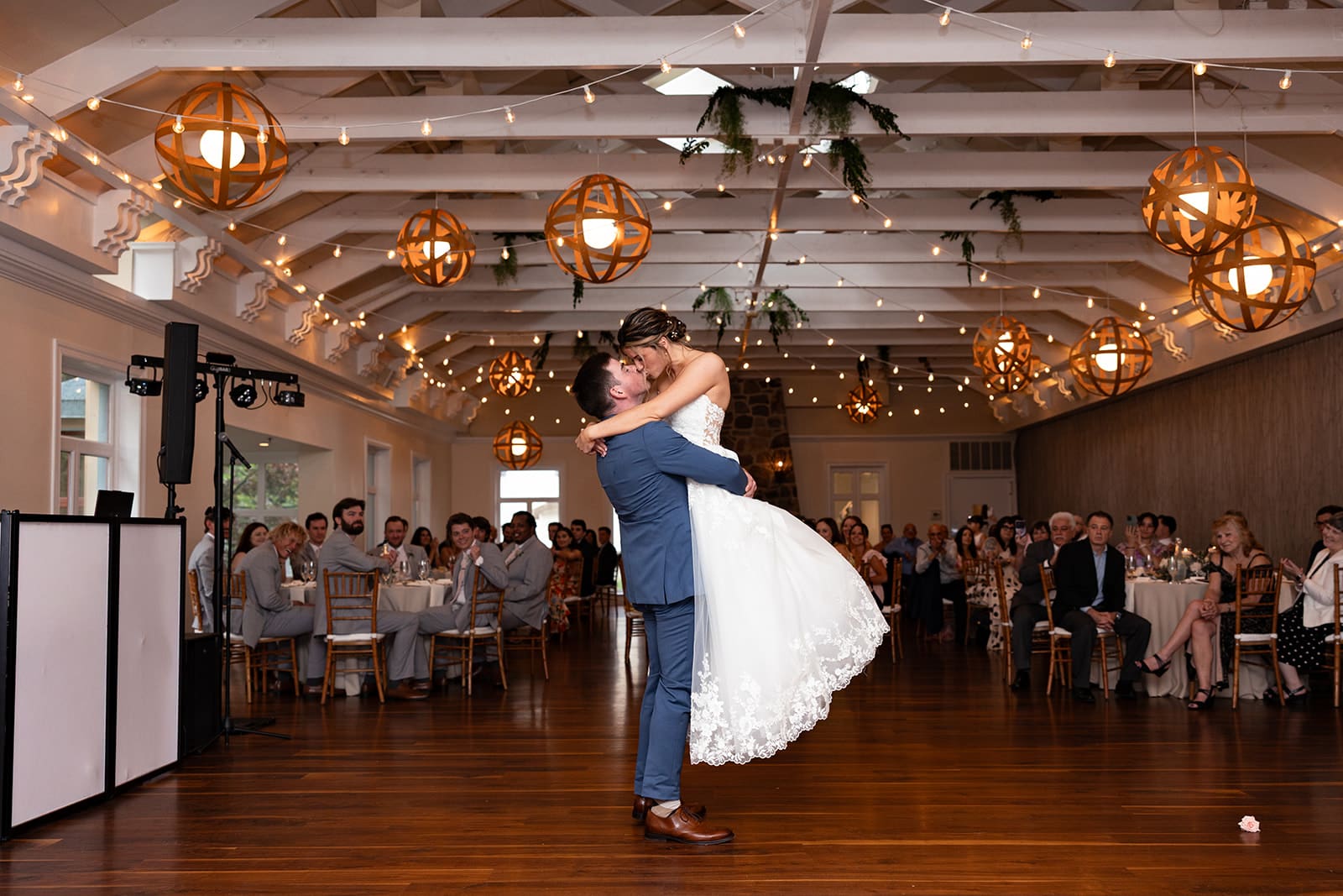 A groom lifts his wife up for a kiss on the dance floor at Pomme Radnor in Padnor PA for their first dance.